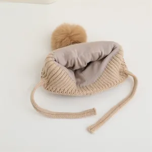 Dettaglio del cappello in maglia beige per neonati con fodera in peluche e pompon soffice