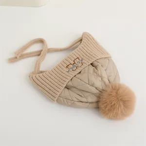 Dettaglio del cappello invernale in maglia beige con motivo trapuntato e pompon