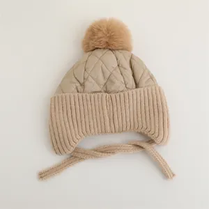 Dettaglio del cappello invernale per neonati con paraorecchie e pompon morbido