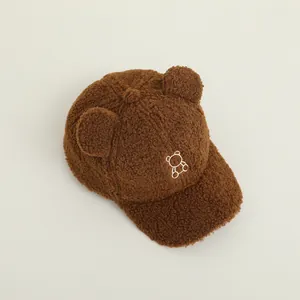 Dettaglio del cappello in lana di agnello marrone per neonati con orecchie e ricamo