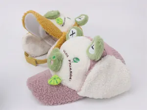 Detail of plush winter sherpa earflap hats with cute frog eyes and GUA FRIENDS embroidery