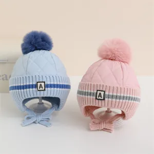 Dettaglio dei cappelli invernali per neonati in rosa e blu con pompon in ecopelliccia