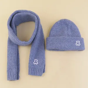 Detailed knit texture of blue winter beanie and scarf set with small bear embroidery