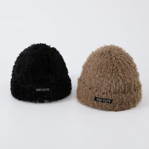 Close-up of thick plush faux fur knit hats in black and tan with DIDI CUTE logo labels