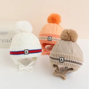 Dettaglio di tre cappelli invernali per bambini con paraorecchie, pompon e maglia M