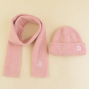 Detail of pink knitted winter set featuring cute white bear embroidery on scarf and hat