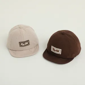Detail of baby corduroy baseball hats in beige and dark brown with soft brims