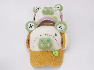 Detail view of plush frog winter hats with ear flaps and embroidery for children