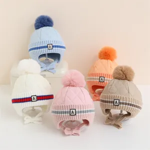 Dettaglio di cappelli invernali per bambini in cinque colori con pompon e paraorecchie