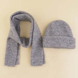 Detail of grey knitted hat and scarf set featuring cute embroidered bear patterns