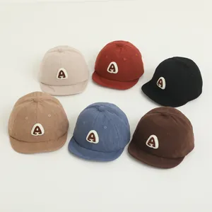 Detailed flat lay of corduroy baby baseball caps in six colors with embroidered A patch