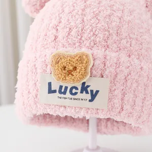 Pink winter knit hat for kids with a cute plush bear patch and soft chenille texture