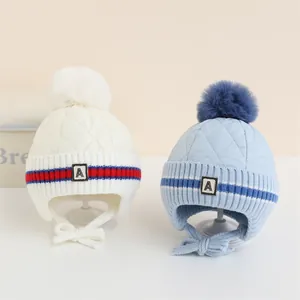 Dettaglio di cappelli invernali a maglia con toppa A, pompon e trama trapuntata