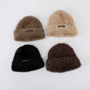 Detailed close-up of fluffy knitted baby hats in four earthy colors with logo labels