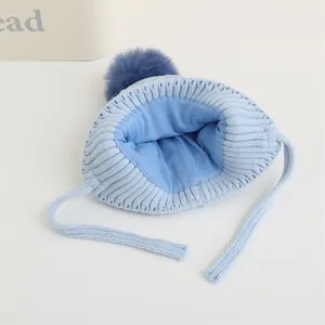 Dettaglio del cappello in maglia celeste per neonati con pompon e morbida fodera interna