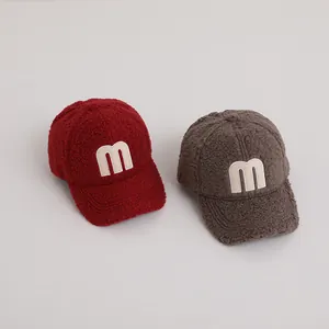 Detailed texture of thick fleece baseball cap with stitched M letter appliqué detail