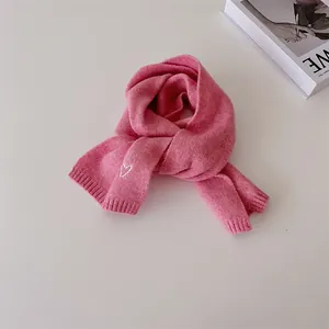 Détail d'écharpe en tricot rose avec broderie cœur blanc et texture de bord côtelé