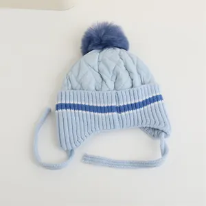 Dettaglio cappello invernale trapuntato azzurro con pompon in ecopelliccia blu navy