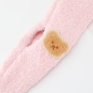 Close-up of soft pink plush fabric texture with a cute brown cartoon bear patch
