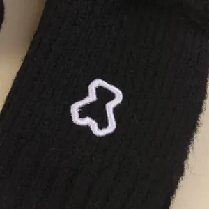 Close-up of black knitted fabric texture with a white embroidered bear outline detail