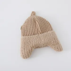 Close-up of baby knit hat showing ribbed texture and plush earflaps in light brown