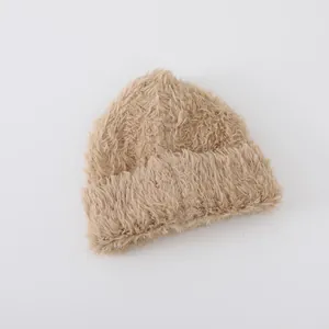Detailed texture of thick beige faux fur knit beanie with a soft plush rolled brim