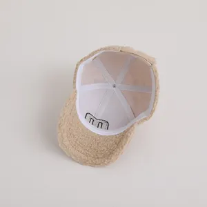 Detail shot of beige fleece baseball cap interior featuring white lining and M letter embroidery