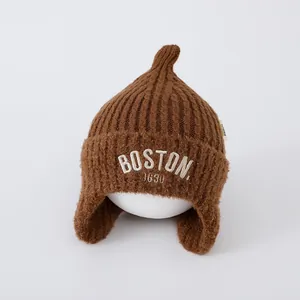 Close-up of brown knit earflap beanie with white Boston 1630 embroidery details