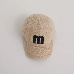 Close-up of beige fleece baseball cap with black M letter patch and warm texture