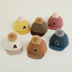 Détail de bonnets en peluche pour bébé avec pompon et broderie lettre A de qualité