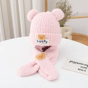 Detailed view of pink plush winter hat and scarf set with Lucky bear emblem
