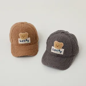 Close-up of teddy fleece texture and embroidered lucky bear patch on kid's baseball caps