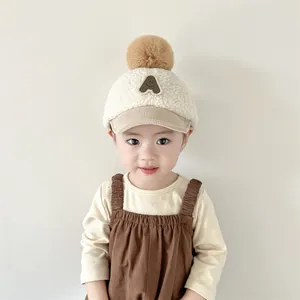 Détail d'une casquette en peluche pour bébé avec pompon doux et broderie lettre A