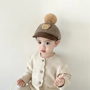 Detail of brown fleece baby baseball cap with bear embroidery and plush pom-pom