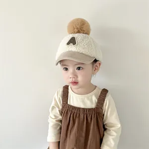 Détail du bonnet d'hiver pour bébé en laine d'agneau avec grand pompon en fausse fourrure