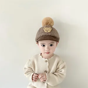 Winter infant baseball hat with bear patch and large faux fur pompom in brown