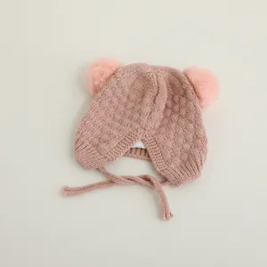 Detalle de gorro de punto rosa para bebé con pompones suaves y forro cálido