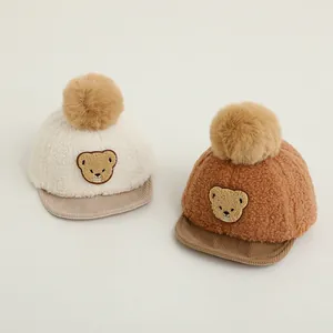 Detail view of baby fleece baseball caps with cute bear patches and faux fur pom-poms