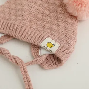 Detalles del gorro de punto rosa para bebé con pompón suave y lazos laterales trenzados