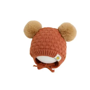 Lindo gorro de punto para bebé con pompones y orejeras en color naranja marrón