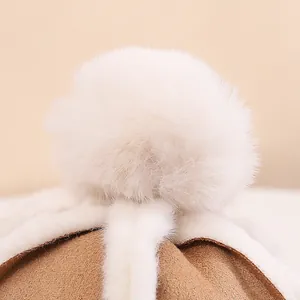Nahaufnahme der kamelbraunen Wildlederoptik-Wintermütze mit weißem Kunstfell-Bommel und Saum