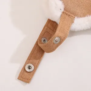 Detail der braunen Wintermütze mit weißem Kunstfellfutter und silbernen Druckknöpfen