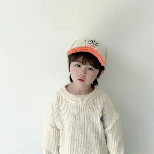 Detail eines Kindes mit warmer Sherpa-Basecap mit orangefarbenem Schirm und Stickerei