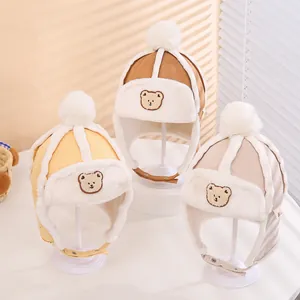 Close-up of three kids winter aviator hats in yellow, brown and beige with pom-poms