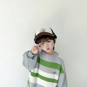 Detail eines Kindes mit gestreiftem Strickpullover und bestickter Sherpa-Baseballkappe