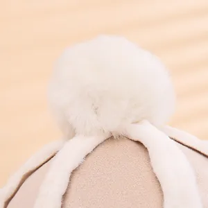 Close-up of thick beige fabric and fluffy white faux fur pompom on children winter hat