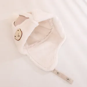 Detailed view of plush child earflap hat with bear embroidery and adjustable strap