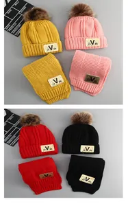 Detailed close-up of knit hat and scarf sets with V labels and fluffy pom poms