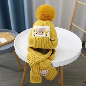 Detailed knit texture of yellow winter baby hat and scarf set with cute bear patch