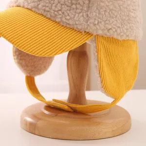 Close-up of plush lamb wool earflap hat with yellow corduroy brim and velcro strap